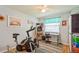 Bedroom area with an exercise bike and a small desk situated beneath a sunny window at 4204 Northwind Ln, Tampa, FL 33624
