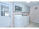 Bright laundry room featuring a side-by-side washer and dryer, plus ample cabinet space and exterior door at 4368 Las Palmas Ave, Spring Hill, FL 34606