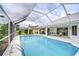Screened in pool featuring a bright blue interior and an adjacent seating area on the home's back patio at 4368 Las Palmas Ave, Spring Hill, FL 34606