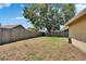 Spacious backyard featuring a wooden fence, lush green grass, and mature trees at 4418 River Overlook Dr, Valrico, FL 33596