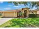 Charming tan home with a two-car garage, well-manicured lawn, and a front yard featuring lovely palm trees at 4418 River Overlook Dr, Valrico, FL 33596
