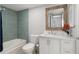 Bathroom featuring white vanity, toilet, and shower with blue tile and a decorative mirror at 500 New York Ave # 23, Dunedin, FL 34698