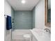 Well-lit bathroom featuring white vanity, toilet, and shower with blue tile at 500 New York Ave # 23, Dunedin, FL 34698