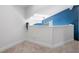 Neutral loft featuring blue accent wall, light carpet, and railing overlooking below at 500 New York Ave # 23, Dunedin, FL 34698