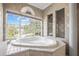 Bright, stylish bathroom featuring a tub with jets, tiled finishing, and natural light coming from a large window at 5160 Loquat Ct, Palm Harbor, FL 34685