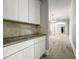 Hallway featuring white cabinetry and granite counters leading to a spacious living area with light wood-look flooring at 5160 Loquat Ct, Palm Harbor, FL 34685