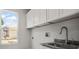 Well-lit laundry room with white cabinets, granite countertops, stainless steel sink, and a window with a pleasant view at 5160 Loquat Ct, Palm Harbor, FL 34685