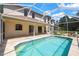 The home's screened-in pool and back exterior featuring multiple windows at 5160 Loquat Ct, Palm Harbor, FL 34685
