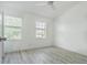 Bright bedroom with gray wood-look flooring, a ceiling fan, and two windows at 6229 Bayside Key Dr, Tampa, FL 33615