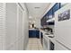 Galley kitchen featuring blue cabinetry, white appliances, and a tile backsplash at 7124 Barclay Ave # A, Spring Hill, FL 34609