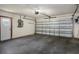 Garage showcasing a large, partially open metal door, white walls, dark painted concrete floor, and side access door at 8332 Berkeley Manor Blvd, Spring Hill, FL 34606