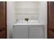Laundry room featuring a white washer and dryer set, overhead wire shelving, and closet with wooden louvered doors at 8332 Berkeley Manor Blvd, Spring Hill, FL 34606