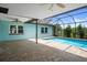 A screened-in pool and patio area featuring brick pavers and a house painted in a light aqua color with white trim at 8332 Berkeley Manor Blvd, Spring Hill, FL 34606