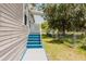 Side view of a charming manufactured home with blue steps, white trim, and a well-maintained lawn with partial fencing at 8471 Fantasia Park Way, Riverview, FL 33578