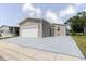 A charming home featuring tan siding, a garage, and a red front door with a freshly painted driveway at 8471 Fantasia Park Way, Riverview, FL 33578