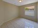 Comfortable bedroom with neutral walls, tiled floors, and a bright window overlooking the backyard at 8812 Bayaud Dr, Tampa, FL 33626