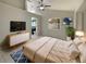Bright bedroom with a ceiling fan, tile flooring, en-suite bathroom, and a modern dresser with TV at 8812 Bayaud Dr, Tampa, FL 33626