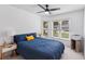 Cozy bedroom with a blue comforter, a yellow accent pillow, and natural light streaming through the windows at 892 Crestridge Cir, Tarpon Springs, FL 34688