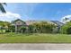Sprawling single-story home with a large green lawn, mature trees, and a screened-in pool area at 892 Crestridge Cir, Tarpon Springs, FL 34688