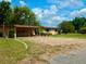 Inviting home with covered parking area, gravel driveway, lush lawn and manicured bushes and plenty of shade trees at 10308 Fore Dr, Tampa, FL 33612