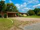 Inviting home with covered parking area, gravel driveway, lush lawn and manicured bushes and plenty of shade trees at 10308 Fore Dr, Tampa, FL 33612