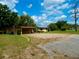 Inviting home with covered parking area, gravel driveway, lush lawn and manicured bushes and plenty of shade trees at 10308 Fore Dr, Tampa, FL 33612