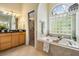 Bright bathroom featuring a soaking tub with a glass block window and a vanity with a black countertop at 10641 Cory Lake Dr, Tampa, FL 33647