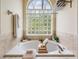 Soaking tub with a glass block window providing natural light and decorative shelving at 10641 Cory Lake Dr, Tampa, FL 33647