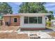 Backyard view of the house with a small patio, fire pit, and an extension with several windows at 1117 Tyrone N Blvd, St Petersburg, FL 33710