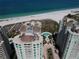 Stunning aerial view of beachfront condos, showcasing pristine white sands, turquoise waters, pool and manicured landscaping at 1180 Gulf Blvd # 306, Clearwater, FL 33767