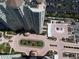Aerial perspective highlighting condo, landscaped entrance, water feature, parking and views of lush greenery and paved parking at 1180 Gulf Blvd # 306, Clearwater, FL 33767