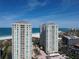 Aerial view of luxurious high-rise buildings on a pristine beach with inviting turquoise waters and manicured landscaping at 1180 Gulf Blvd # 306, Clearwater, FL 33767