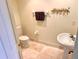 Cozy half bathroom with pedestal sink, tiled floors, decorated with golden palm tree accent at 1180 Gulf Blvd # 306, Clearwater, FL 33767