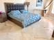 Comfortable bedroom with stylish grey headboard, blue comforter, white desk and tiled flooring at 1180 Gulf Blvd # 306, Clearwater, FL 33767