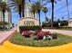 Welcoming community entrance with stone signage, colorful flower beds, lush landscaping, and condominium buildings at 1180 Gulf Blvd # 306, Clearwater, FL 33767