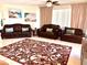 Inviting living room featuring brown leather couches, patterned rug, and beach themed art at 1180 Gulf Blvd # 306, Clearwater, FL 33767