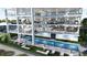 Exterior view of a modern condo building featuring a pool, sun loungers, outdoor seating, and multiple balconies at 14048 Gulf Blvd # 201, Madeira Beach, FL 33708