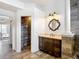 Tastefully decorated bathroom featuring wood look floors, a wood vanity with stone top, and decorative mirror at 1443 Obear Ct, Wesley Chapel, FL 33543