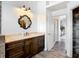 Tastefully decorated bathroom featuring wood look floors, a wood vanity with stone top, and decorative mirror at 1443 Obear Ct, Wesley Chapel, FL 33543