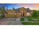 Inviting single-story home features a three-car garage, red front door, and manicured landscaping at dusk at 1443 Obear Ct, Wesley Chapel, FL 33543
