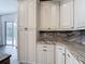 Kitchen features white cabinets with dark hardware, granite countertops, and view of the outdoor pool at 1443 Obear Ct, Wesley Chapel, FL 33543