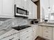 Kitchen with granite counters, stainless steel appliances, dark hardware, and white cabinets at 1443 Obear Ct, Wesley Chapel, FL 33543