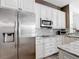 Modern kitchen features stainless steel refrigerator and appliances with white cabinetry and granite countertops at 1443 Obear Ct, Wesley Chapel, FL 33543