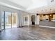 Bright open-concept living space with wood-look tile, flowing into the modern kitchen and overlooking the screened lanai at 1443 Obear Ct, Wesley Chapel, FL 33543