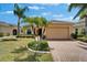 Inviting single-story home featuring a two-car garage, well-manicured lawn, and mature palm trees at 1643 Emerald Dunes Dr, Sun City Center, FL 33573