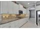 Close-up of a well-equipped kitchen featuring granite countertops, backsplash, and white cabinets at 1643 Emerald Dunes Dr, Sun City Center, FL 33573