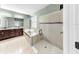 Bathroom showcasing a glass enclosed shower, soaking tub, double vanity sinks, and tiled floors at 17610 Buckingham Garden Dr, Lithia, FL 33547