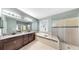 Bathroom featuring a double vanity, large mirror, garden tub with tile surround and glass enclosed shower at 17610 Buckingham Garden Dr, Lithia, FL 33547