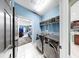 Light-filled laundry room with modern washer and dryer set, storage shelf and neutral walls at 17610 Buckingham Garden Dr, Lithia, FL 33547