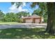 Spacious brick home with a three-car garage, American flag, and long driveway surrounded by mature trees at 1815 Durant Rd, Valrico, FL 33596